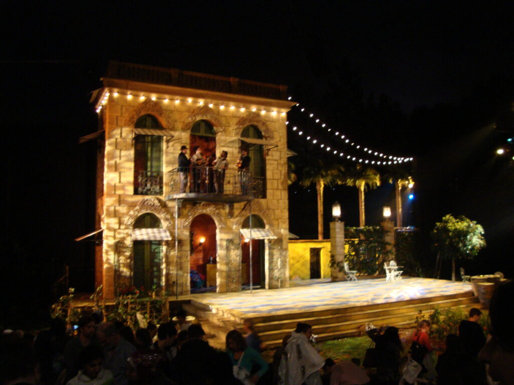 Stage set of a building, which has people on a balcony, at night time